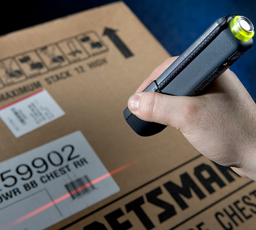 A hand scanning a label's barcode with a handheld scanner.