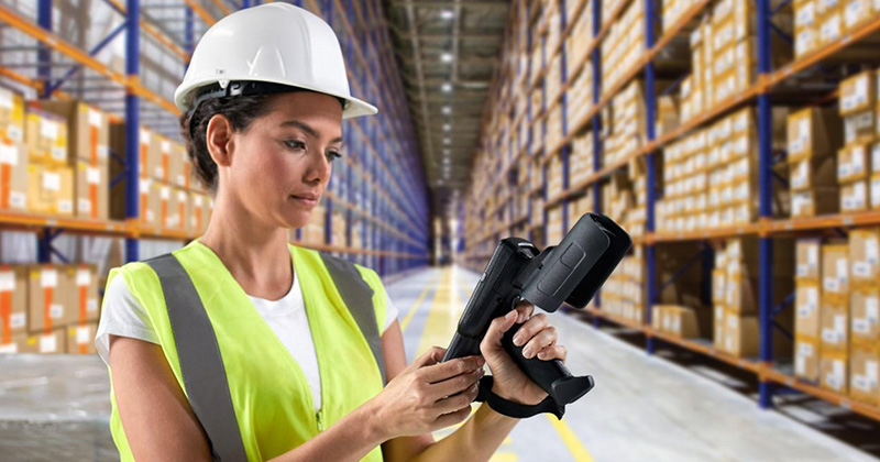 A woman in a distribution center reviewing an item on her scanner.