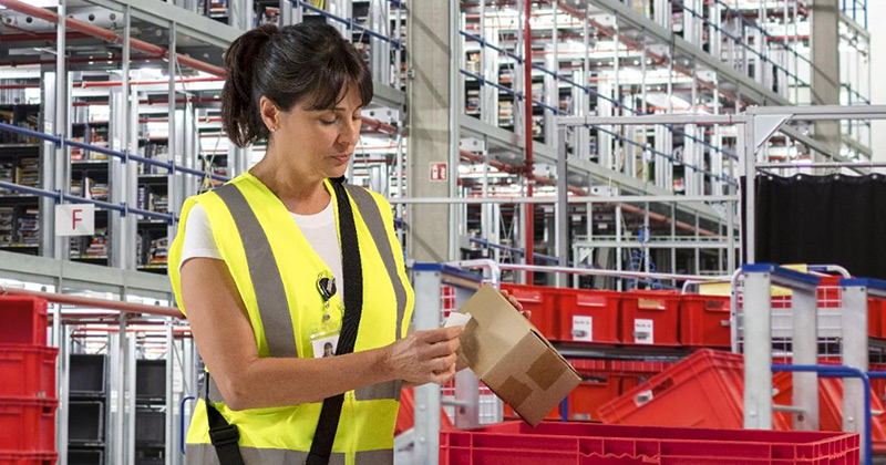 A woman in a distribution center looking at a printed label.